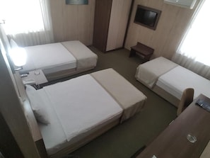 A hotel room with two single beds, a small table, a TV, and a window with curtains. - Hosta Otel (Adana)