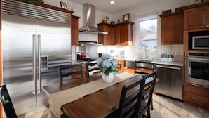 Una cocina moderna con electrodomésticos de acero inoxidable, armarios de madera y un comedor con mesa y sillas.