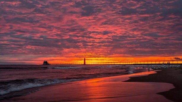 Una playa con un muelle que se adentra en el océano durante el atardecer.