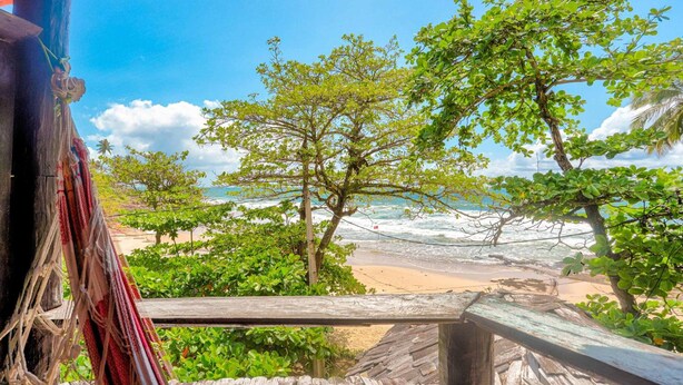 A wooden structure with a view of a beach and ocean. - Pousada Terral Surf (Itacaré)