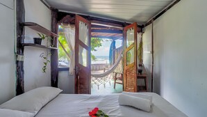 A bedroom with a bed, a hammock, and a view of the beach. - Pousada Terral Surf (Itacaré)
