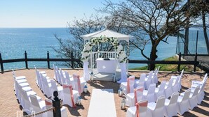 Hochzeitszeremonie mit einem weißen Gazebo, Stühlen und einem weißen Gang.