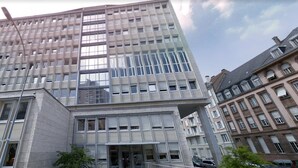 Ein modernes Gebäude mit einer rasterförmigen Fassade, großen Fenstern und einem markanten Eingang.