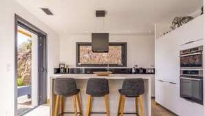 Uma cozinha moderna com ilha central, banquetas e eletrodomésticos embutidos.