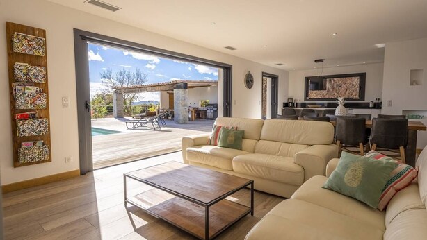 Uma sala ampla com um sofá grande, uma mesa de centro e um espaço de jantar com cadeiras.