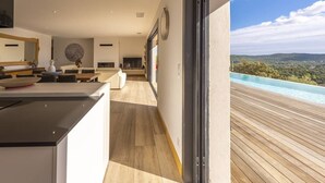 Interior moderno com cozinha, sala de jantar e vista para uma piscina.