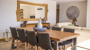 Uma sala de jantar com uma mesa de madeira, cadeiras pretas, um espelho grande e uma tigela decorativa.
