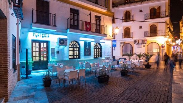 A restaurant with outdoor seating, a sign reading "PLATELIER," and a tiled courtyard. - Hotel Platería by Bossh Hotels (Ecija)