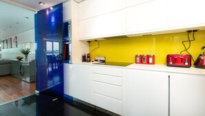 A modern kitchen with white cabinets, a yellow backsplash, and red appliances. - River view Luxury 3bed flat with views (London)