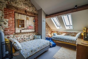 A bedroom with two beds, a brick wall, and skylights.