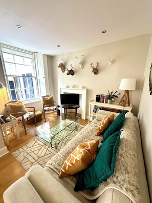 A living room with a sofa, chairs, a TV, and wall-mounted deer antlers. - Chic Edinburgh City Centre Apart. close to Castle (Edinburgh)