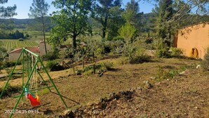 Paisaje rural con un columpio, un edificio de techo rojo y un campo al fondo.