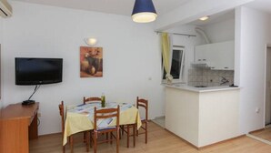 A compact living space with a dining area, a kitchen, and a TV. - Apartments Posta - Comfort Studio with Balcony and Sea View (Saplunara)