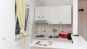 A compact kitchen with white cabinets, a sink, and a countertop with utensils. - Apartments Posta - Comfort Studio with Balcony and Sea View (Saplunara)