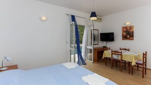 A bedroom with a bed, a desk, a chair, a table, and a television. - Apartments Posta - Comfort Studio with Balcony and Sea View (Saplunara)