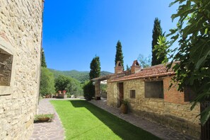 A stone building with a tiled roof, a stone pathway, and a well-maintained lawn.