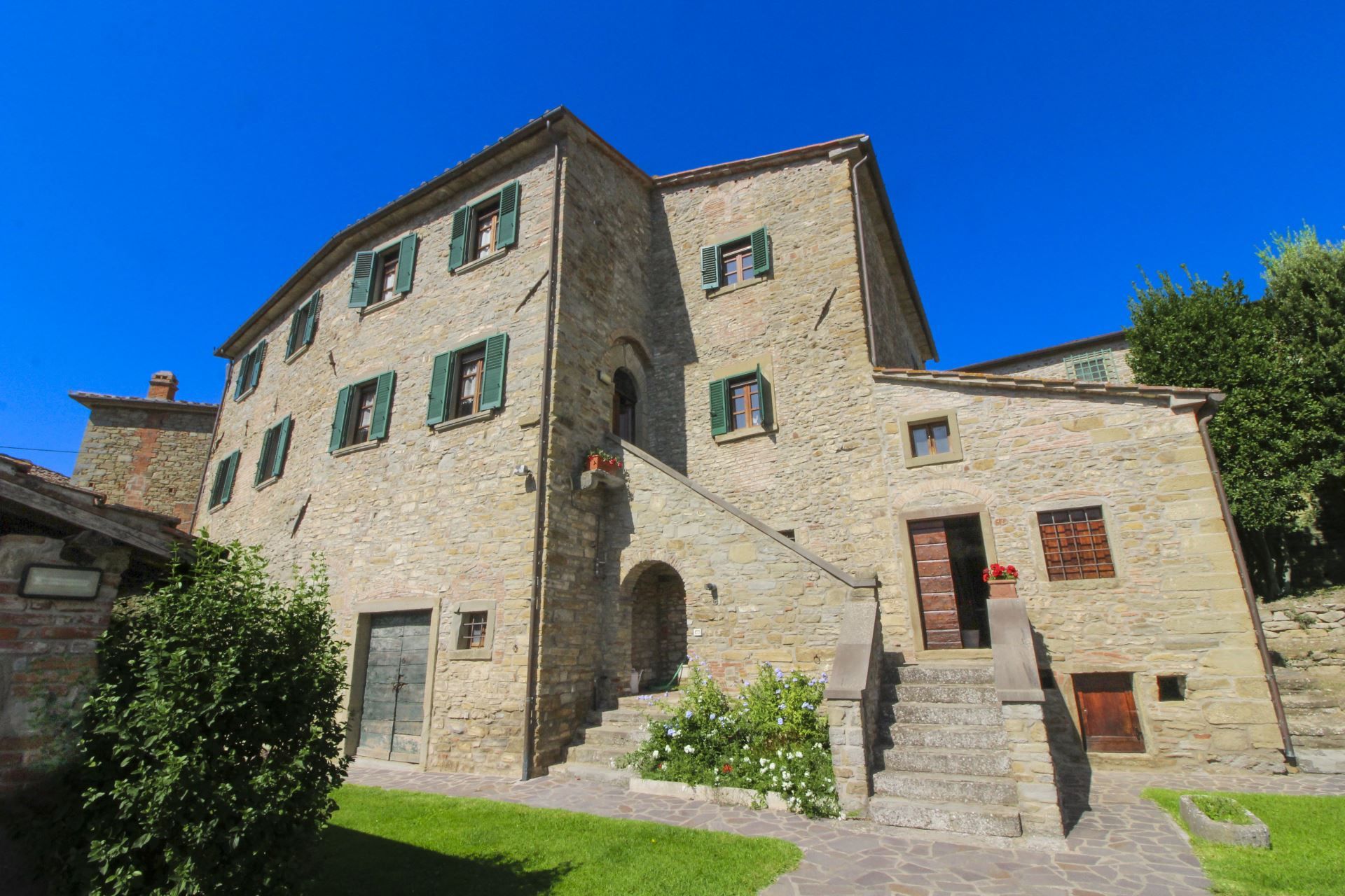 A stone building with multiple windows and a staircase leading to the entrance.