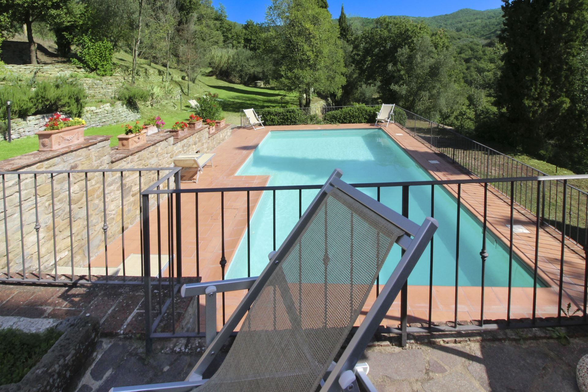 Una piscina con vistas a un jardín ajardinado y colinas.