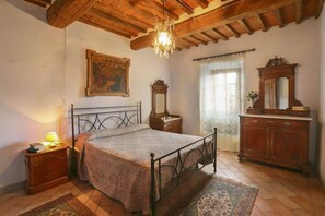 A bedroom with a bed, wooden dresser, and a chandelier.