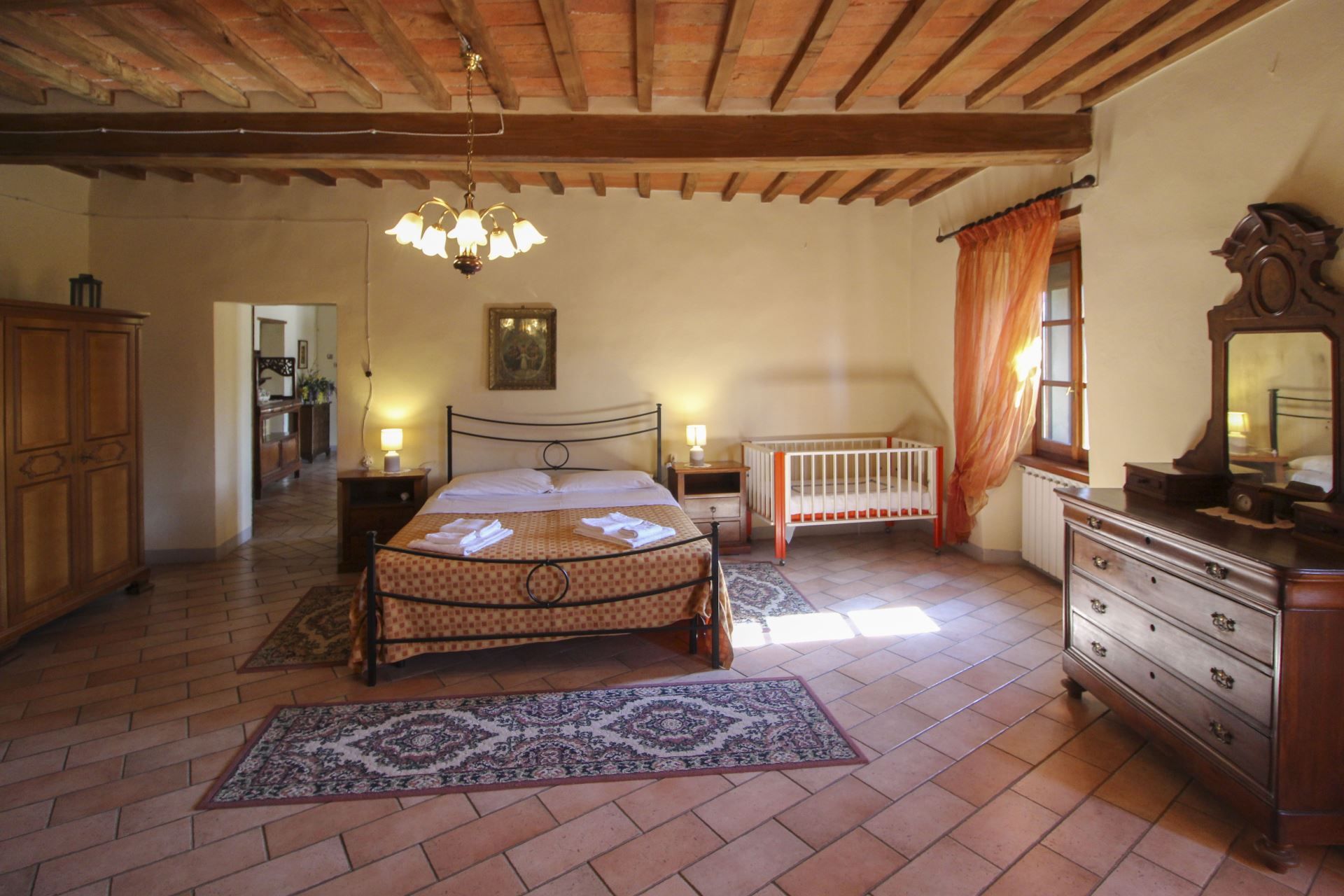 Un dormitorio con cama, cuna, cómoda, candelabro y alfombra estampada.