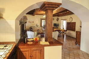 A kitchen with a gas stove, wooden cabinets, and a fruit bowl on the counter.