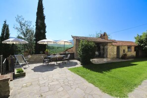 A patio with stone flooring, outdoor furniture, and umbrellas.