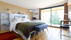 A modern bedroom with a large bed, a desk, and a view of greenery outside. - Chambre d'hotes Saga (Savignac-Mona)