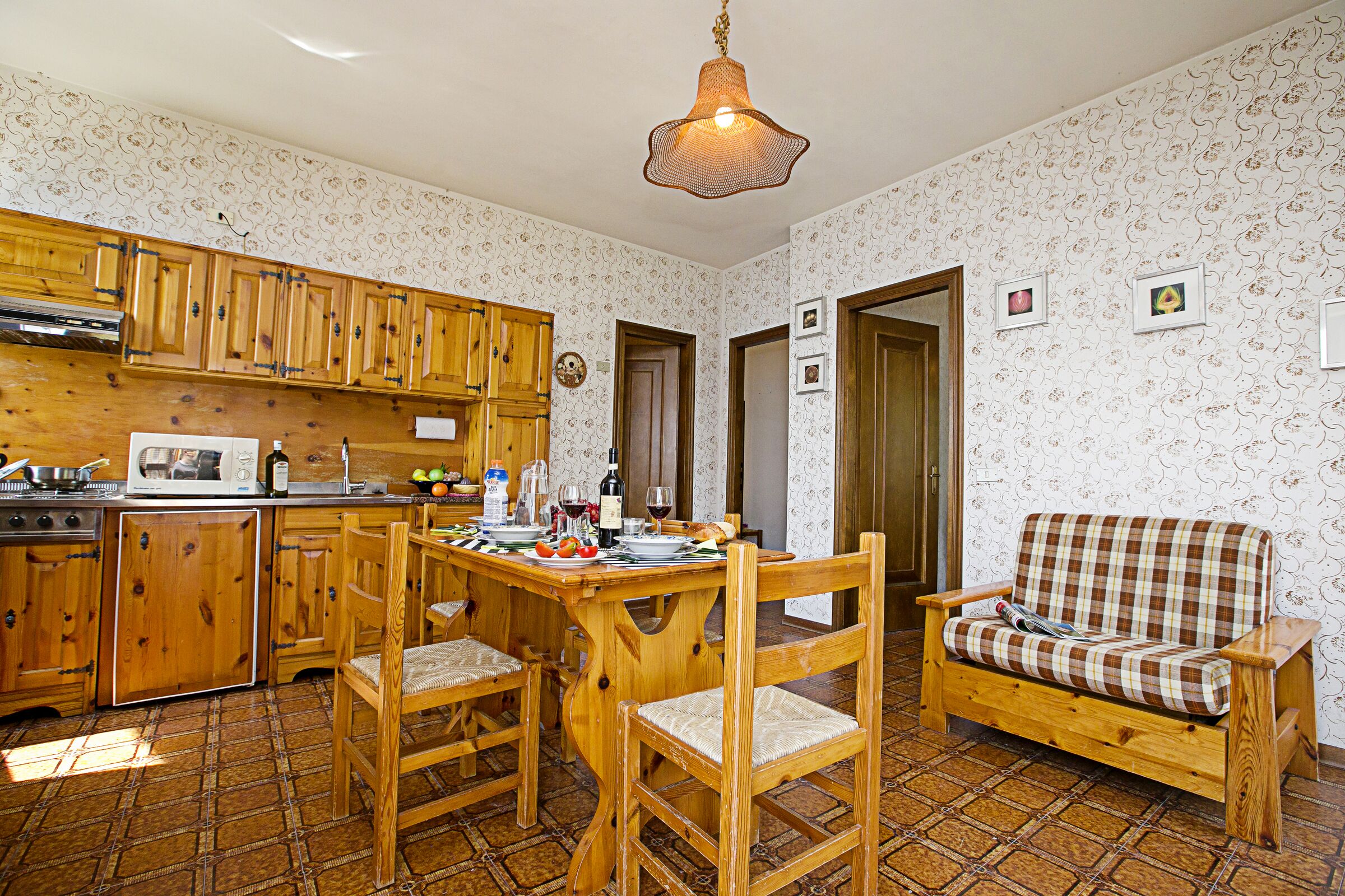 Una cucina con mobili in legno, un tavolo da pranzo, sedie e un divano.