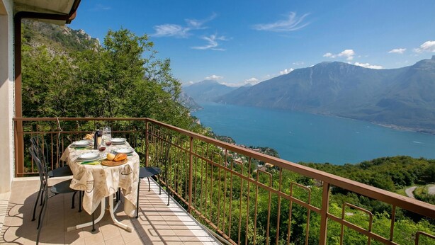 A balcony with a table set for dining, overlooking a mountainous landscape and a lake. - Tremosine Wonderful Lake View 2, Tremosine, Italy (Tremosine)