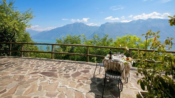 A stone patio with a table set for two, overlooking a mountainous landscape.