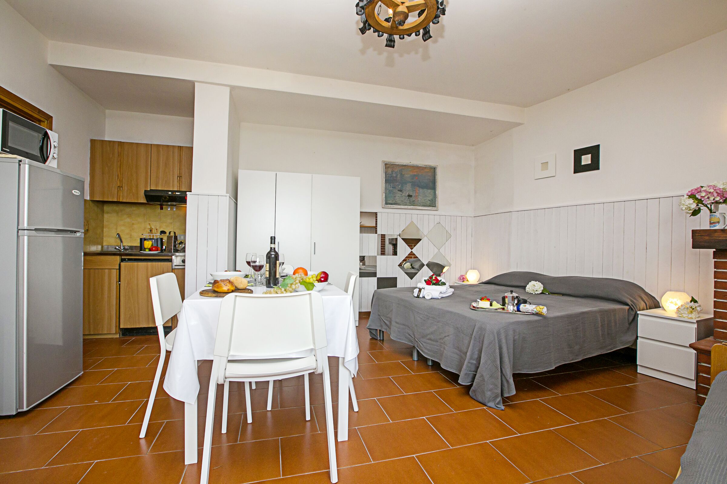 Een kleine leefruimte met een keuken, eethoek en een bed.