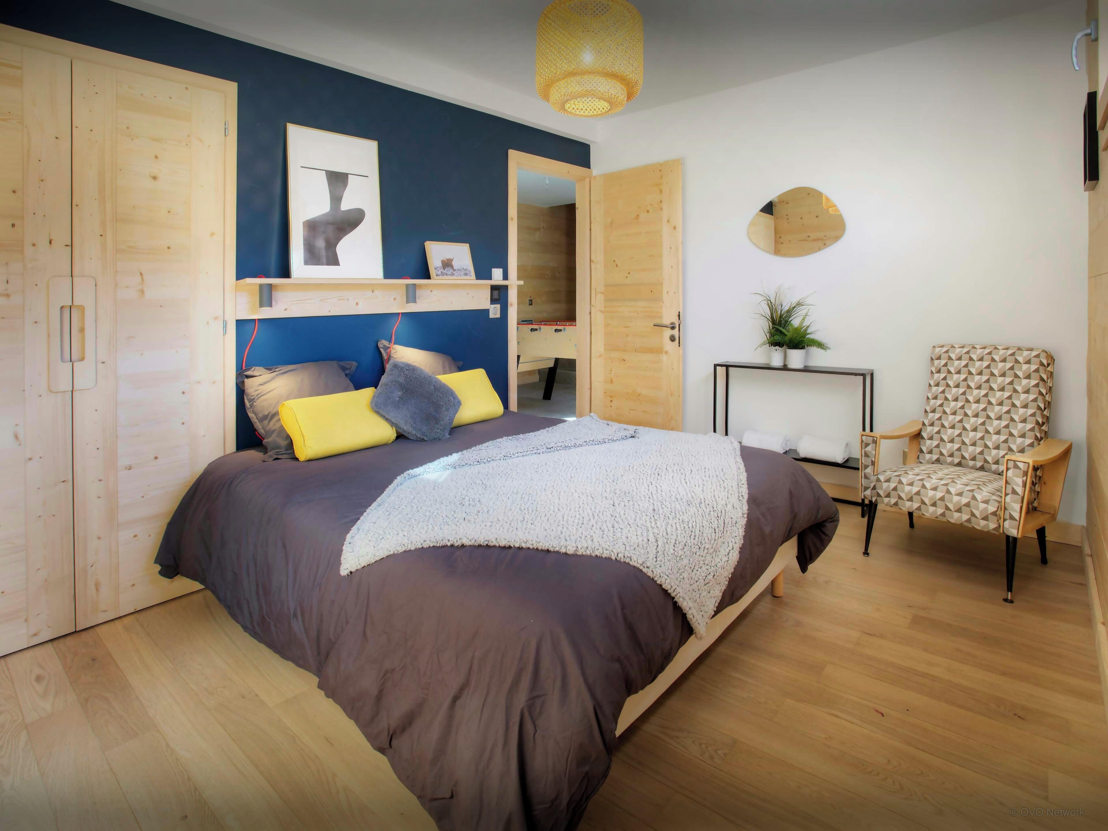 Une chambre avec un grand lit, une armoire en bois et une chaise.