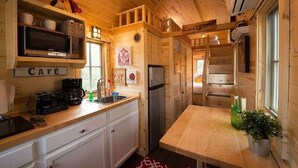 Interior de una cabaña de madera con kitchenette, una mesa de comedor y un cartel que dice 'Welcome'.