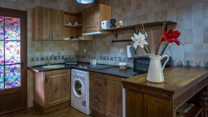 Una cocina con armarios de madera, lavadora, lavaplatos y un florero con flores en la encimera.