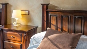 Habitación de hotel con cabecera de madera, una mesita de noche con lámpara y una cama con almohadas.