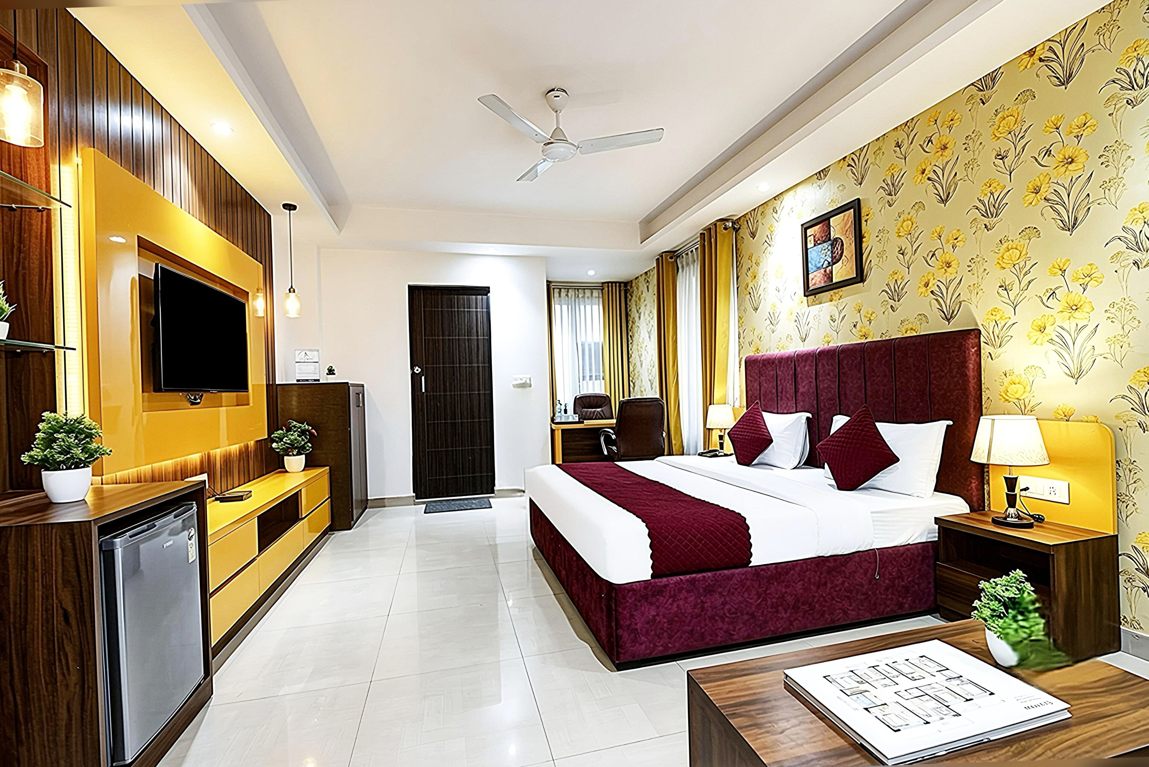 A hotel room with a bed, bedside tables, a TV, a ceiling fan, and a bathroom visible through an open door.