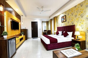 A hotel room with a bed, bedside tables, a TV, a ceiling fan, and a bathroom visible through an open door. - Hotel Perfectionist by Kelvish Hotel (New Delhi)