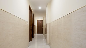 Un pasillo con paredes y suelo de baldosas, que conduce a una puerta de madera al final.