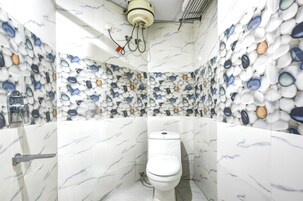 Un bagno con il water, pareti a effetto marmo e scaldabagno a soffitto.