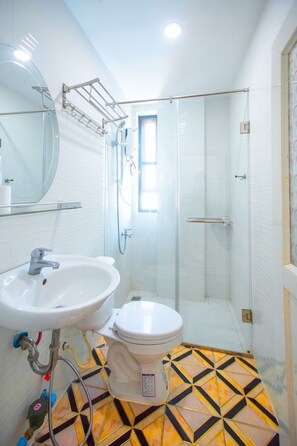 Ein Badezimmer mit weißem Waschbecken, Toilette und einer Duschkabine aus Glas.