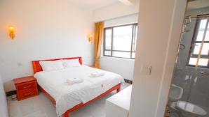 A hotel room with a bed, bedside table, and a shower area. - Cambodia Eren Hotel (Phnom Penh)