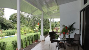 A covered patio with a table and chairs, surrounded by potted plants and a well-maintained garden. - Villas Octogoña (Ciudad Cortés)