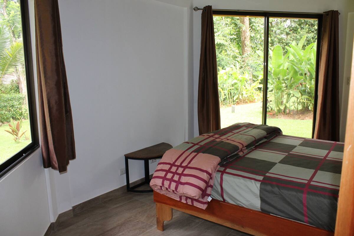 A bedroom with a bed, a small table, and a window with curtains.