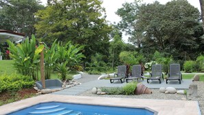 A swimming pool with steps leading into it, surrounded by a garden with various plants and a gazebo in the background. - Villas Octogoña (Ciudad Cortés)
