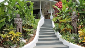 A staircase leading to a covered porch with statues and lush tropical plants. - Villas Octogoña (Ciudad Cortés)