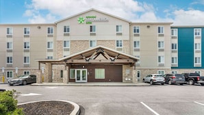 Ein Stay America Hotel mit Stein-Fassade, mehreren Parkplätzen und blauem Himmel.