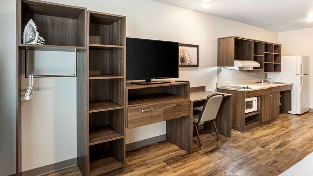 Eine moderne Küche mit Holzsäulen, einem Einbauofen und einem großen Flachbildfernseher.