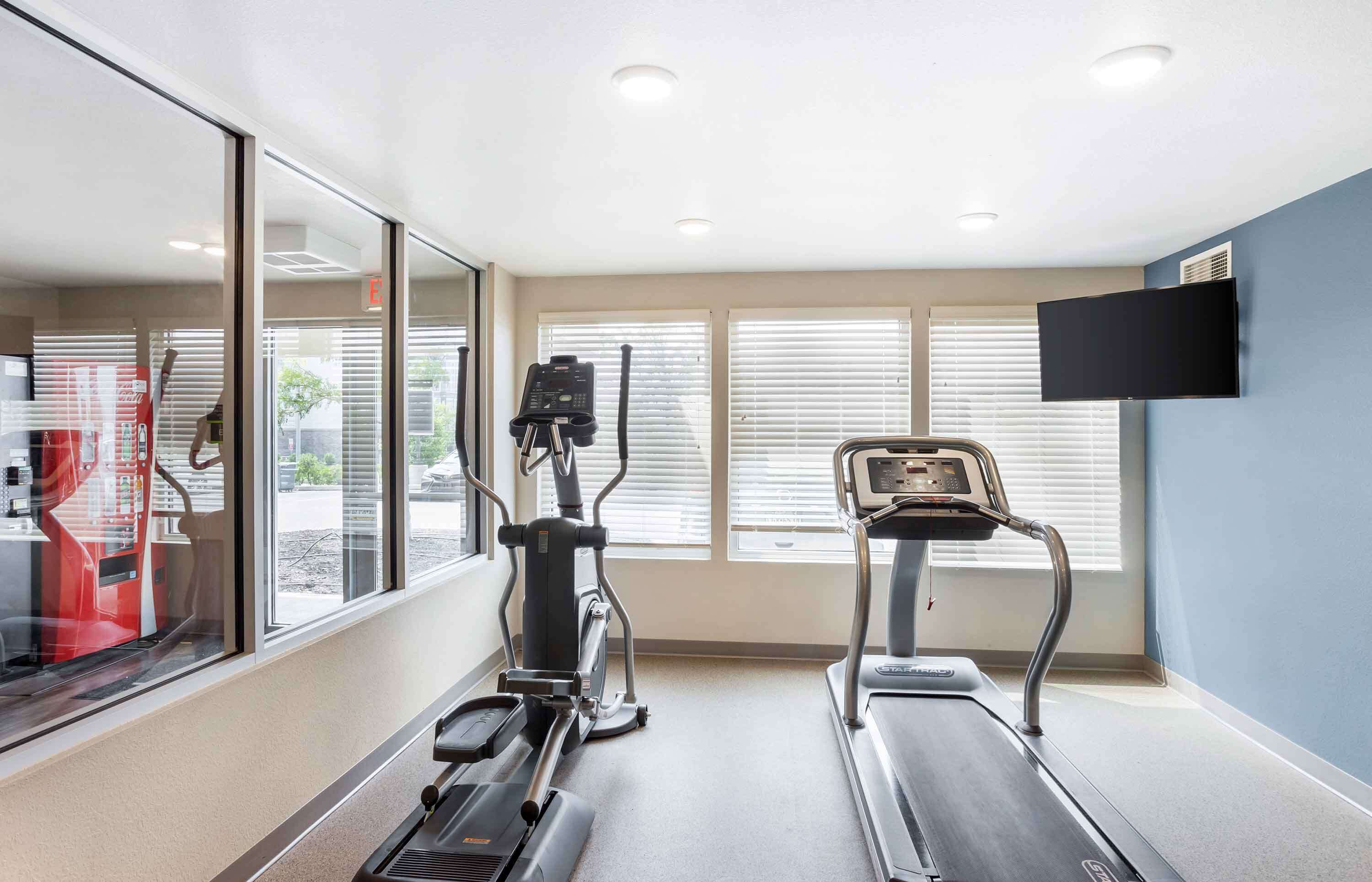 Une salle de remise en forme équipée de tapis de course, d’un vélo elliptique et d’un vélo d’appartement.