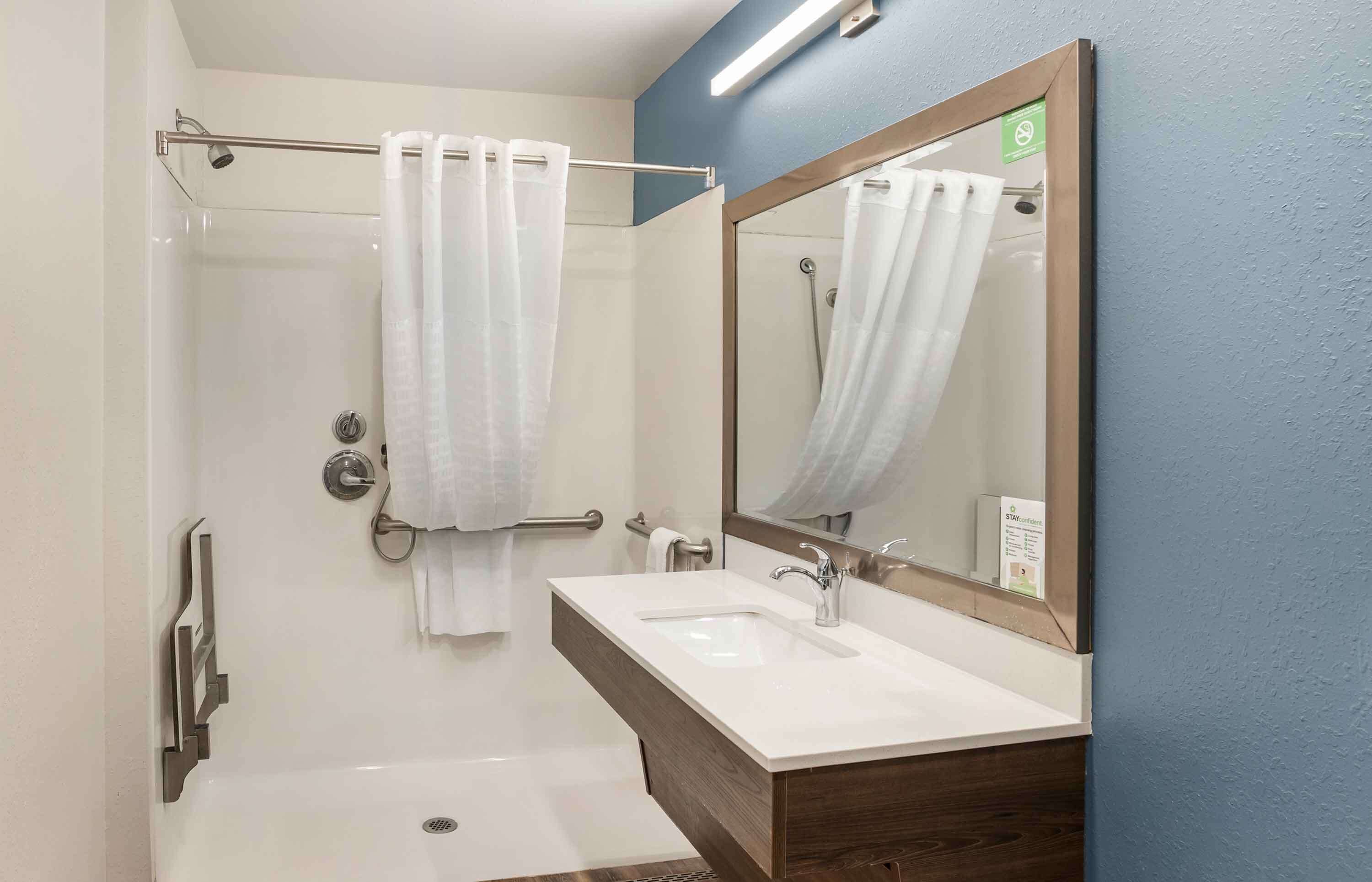 A modern bathroom with a shower, a sink, and a mirror.