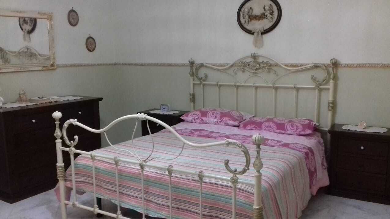 Una camera da letto con un letto, una cassettiera, un comodino e una sveglia a muro.